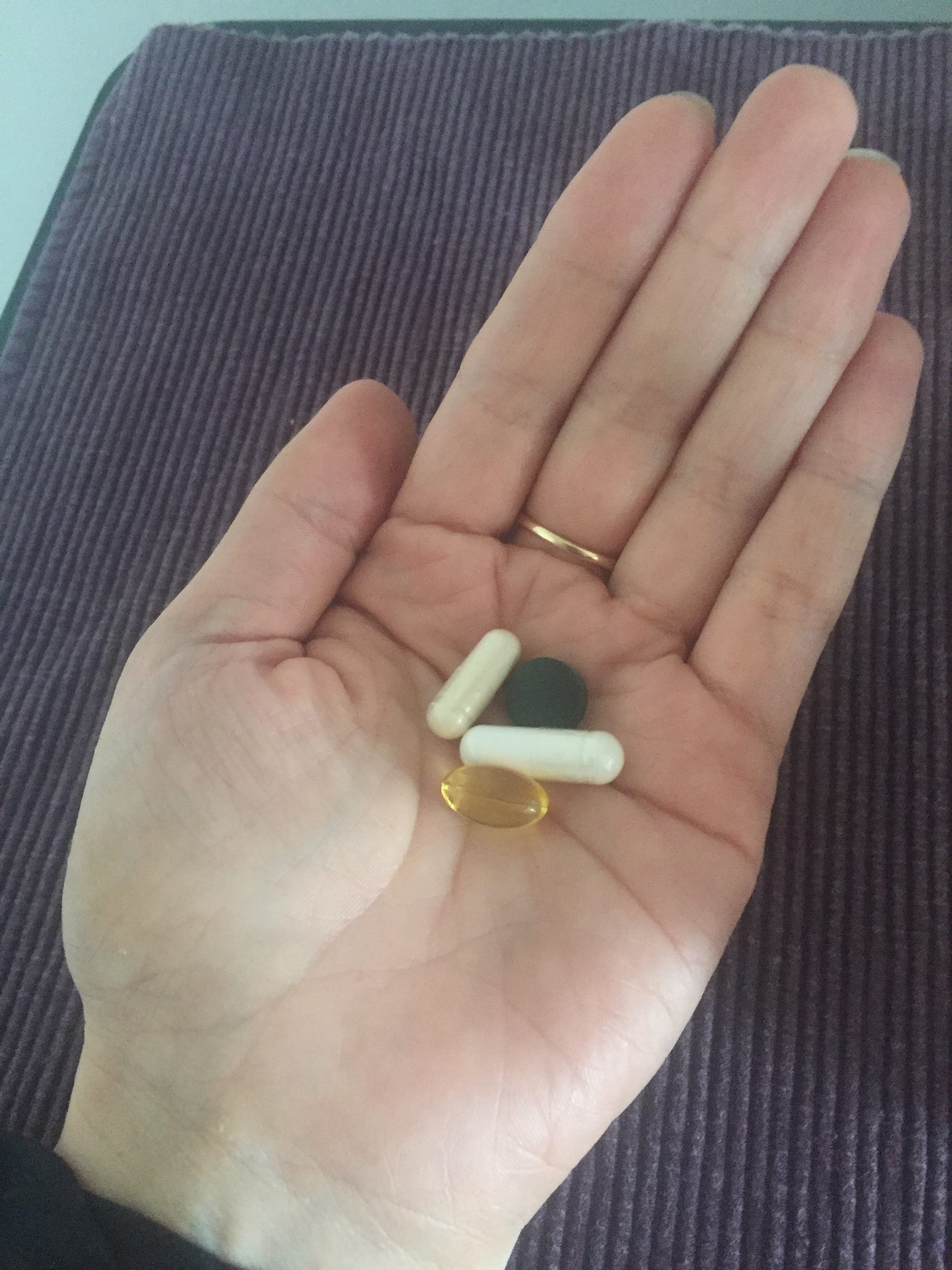 Niacinimide, Biotin, Omega 3 and Spirulina supplements in hand